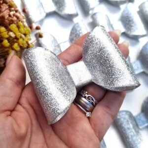APLIQUE EM ACRÍLICO LAÇO GLITTER PRATA 2X6,5X5 CM UND
