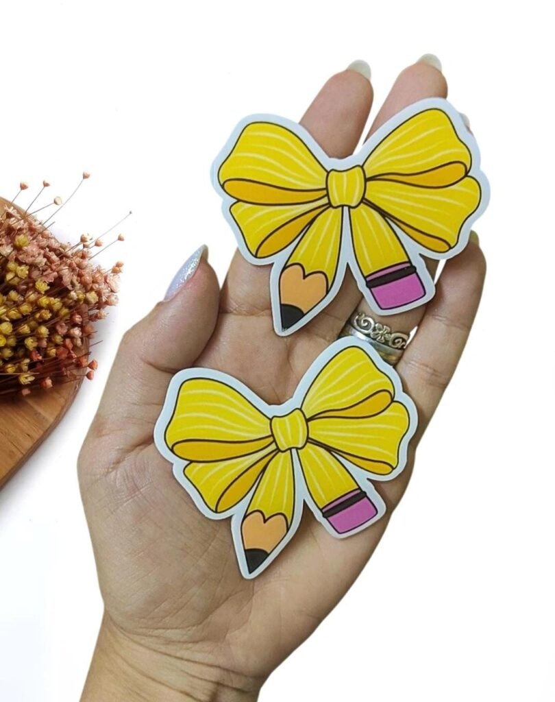 APLIQUE EM ACRÍLICO CURVADO LÁPIS EM FORMA DE LAÇO 7CM UND