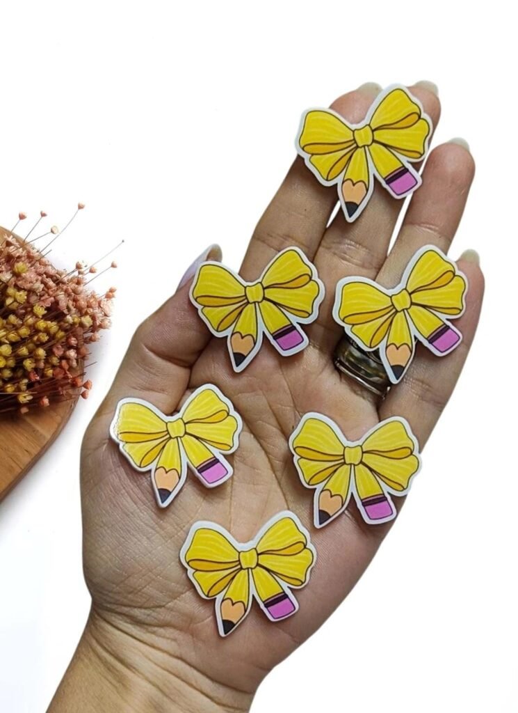 APLIQUE EM ACRÍLICO P/ LAÇO LÁPIS EM FORMA DE LAÇO 4CM UND