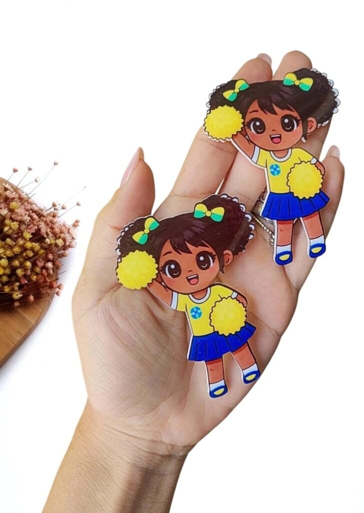 APLIQUE EM ACRÍLICO CURVADO SUBLIMATICO MENININHA MASCOTE COPA C/ POMPOM AMARELO 8 CM UND